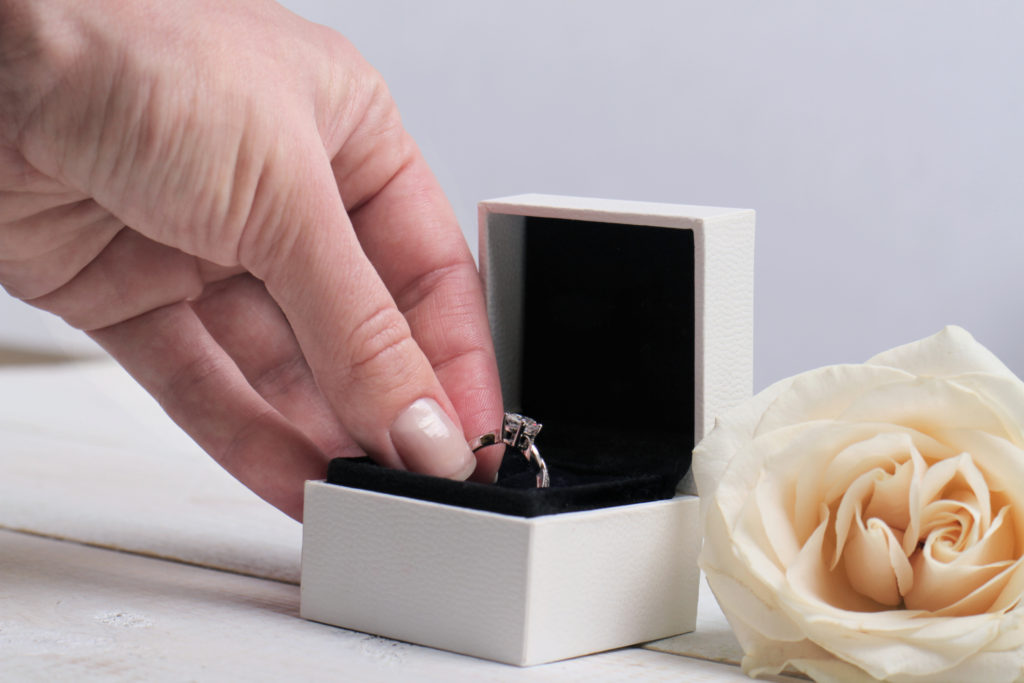 Engagement ring box in bride hands. Closeup of woman hand holding jewellery. Love, Wedding, Proposing, Marriage concept.